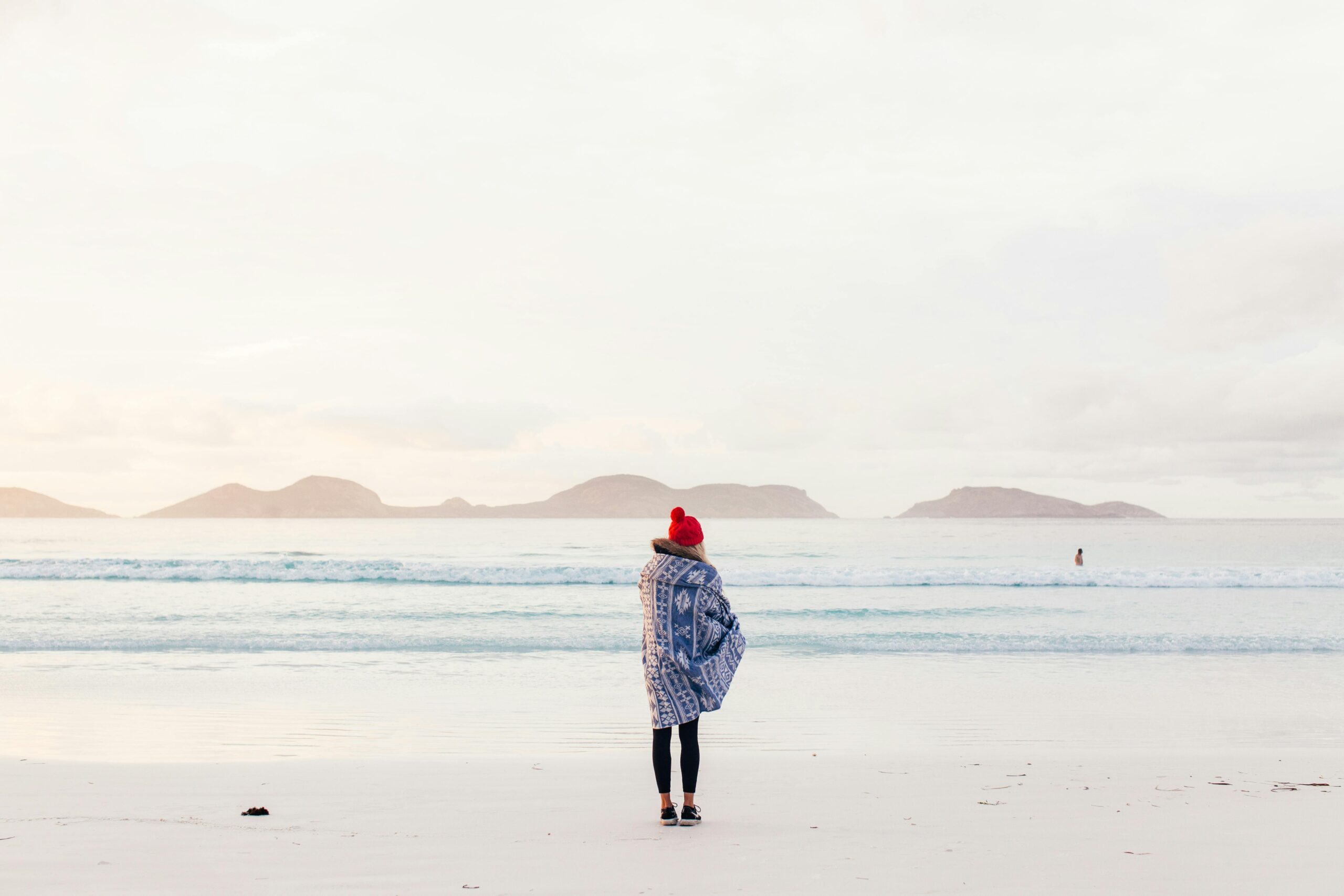 Woman standing on the beach in winter. Manly, Sydney.